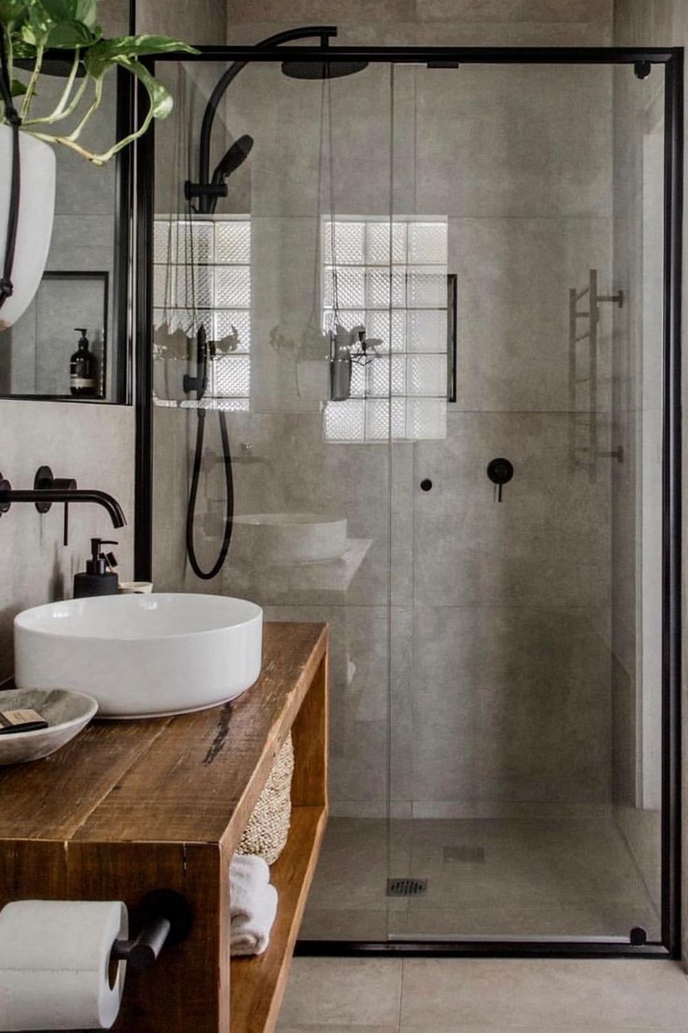 A contemporary rustic industrial bathroom featuring a frameless shower design, rustic wood vanity, and elegant accessories.