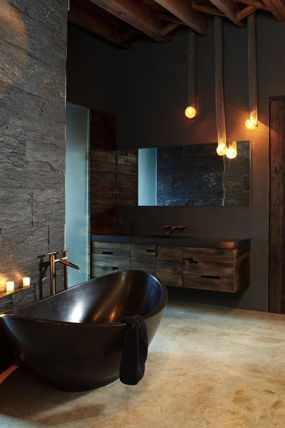 Stylish rustic industrial bathroom design featuring a black freestanding bathtub and modern wooden vanity.