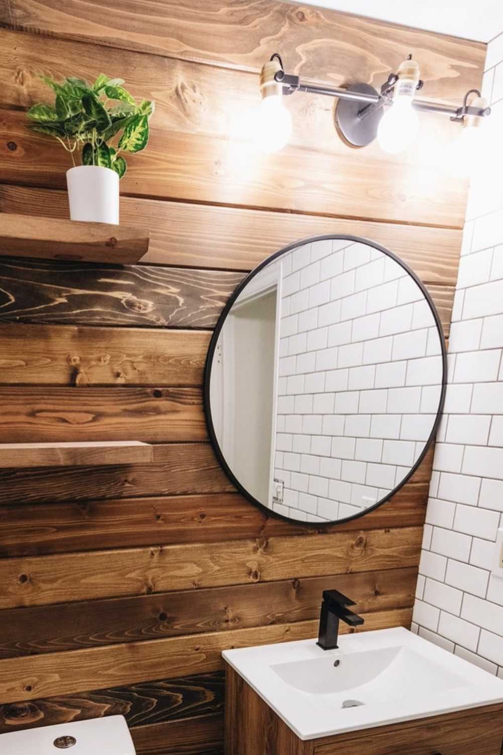Beautiful rustic industrial bathroom design featuring warm wood accents and a round mirror.