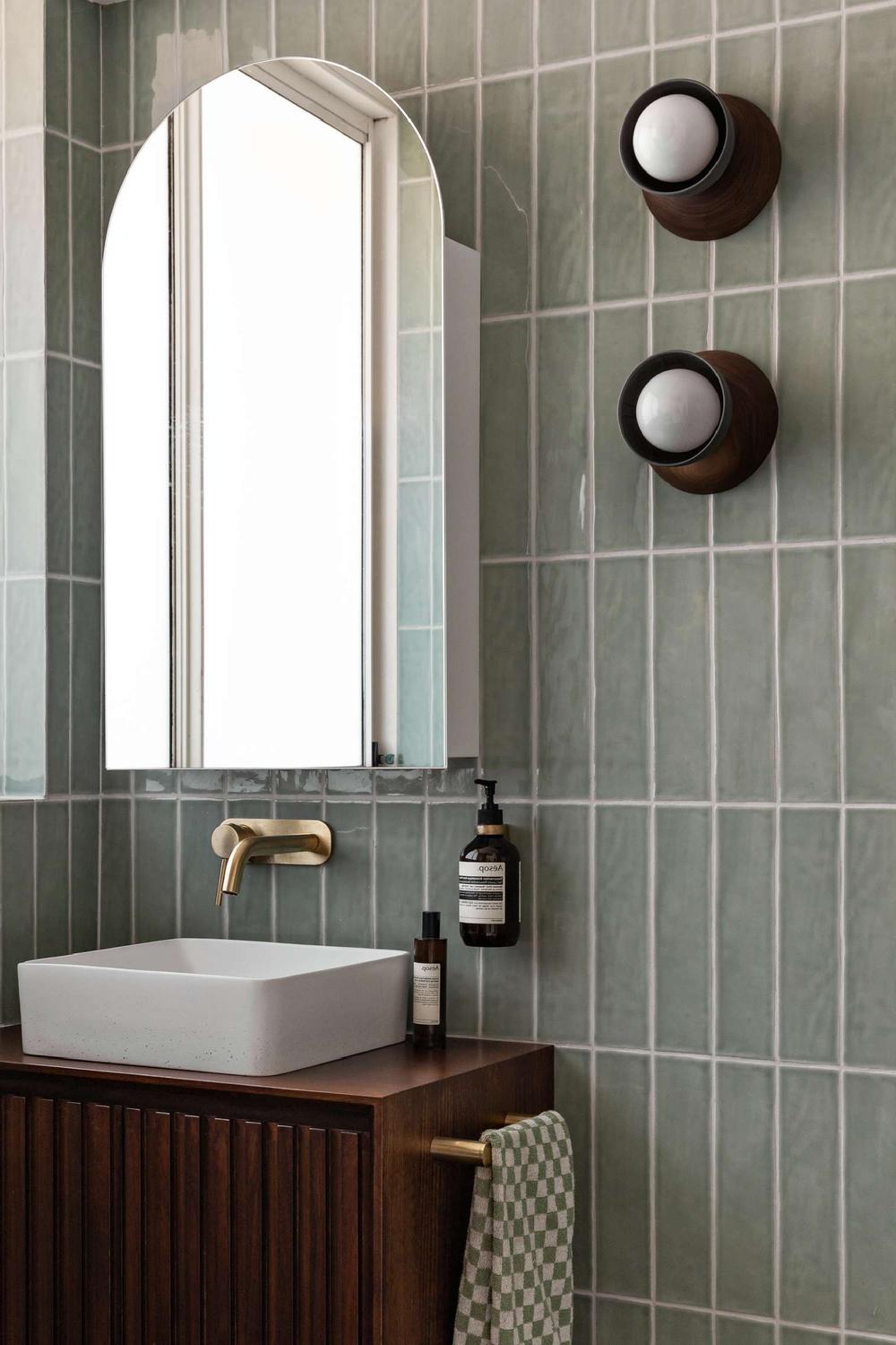Sophisticated bathroom with sage green tile walls and decorative elements.