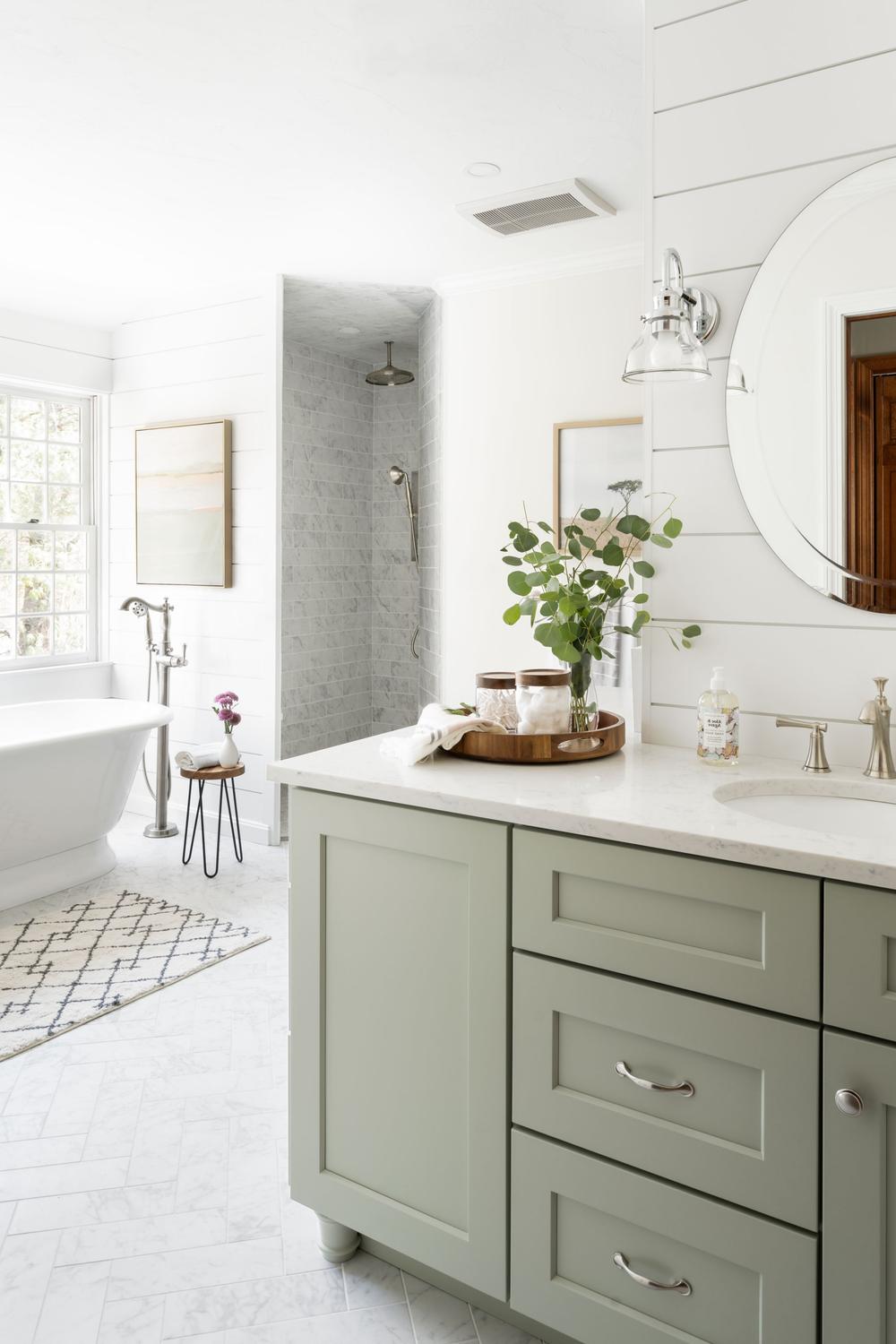 Classic sage green vanity with modern design elements and a freestanding bathtub.