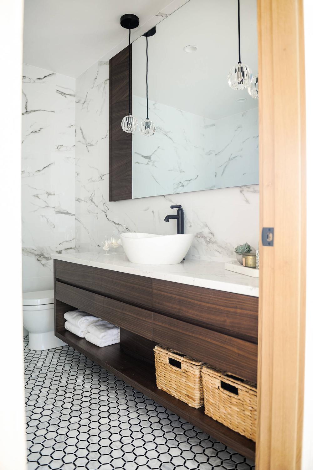 Baño escandinavo moderno con azulejos de mármol y mueble de madera oscura