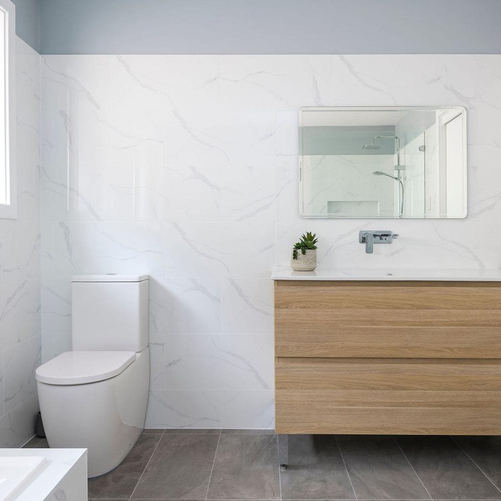 Baño escandinavo moderno con azulejos de mármol oscuro y accesorios dorados
