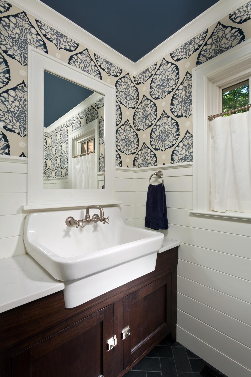 Bathroom showcasing navy blue and cream leaf patterned wallpaper alongside shiplap treatment