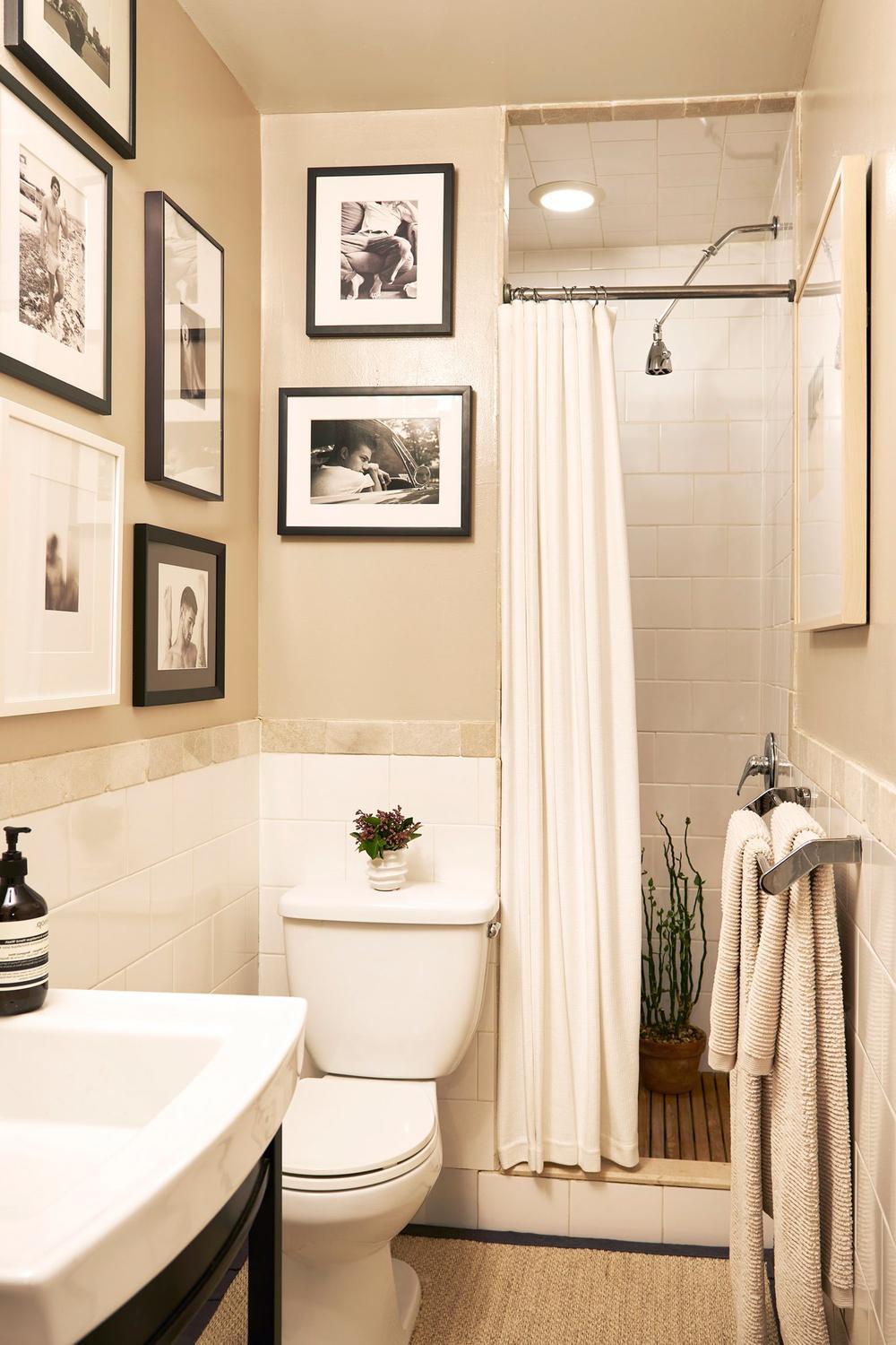Functional small bathroom with light neutral walls and black-and-white gallery art
