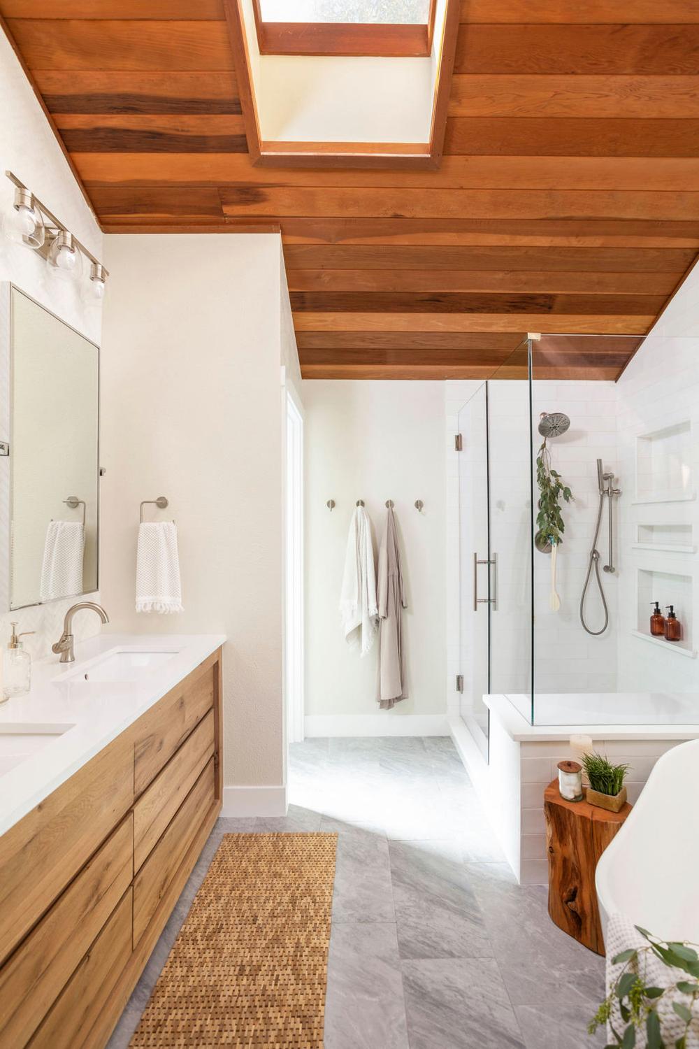 Baño acogedor con techo de listones y ventanas grandes
