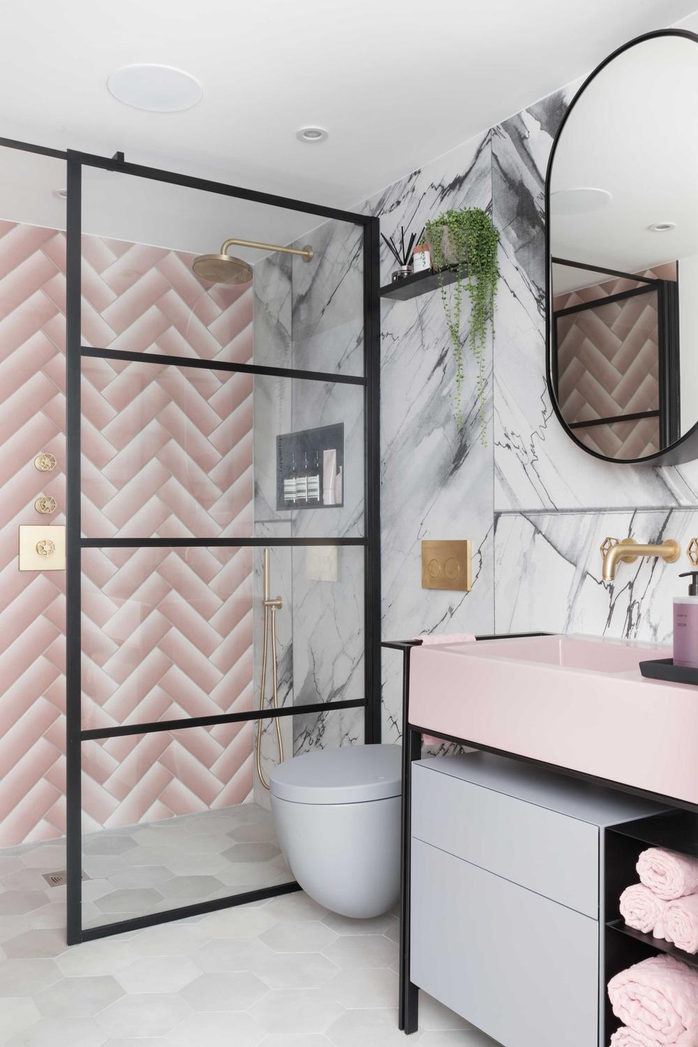 Modern small bathroom with pink herringbone tiles and gold accents