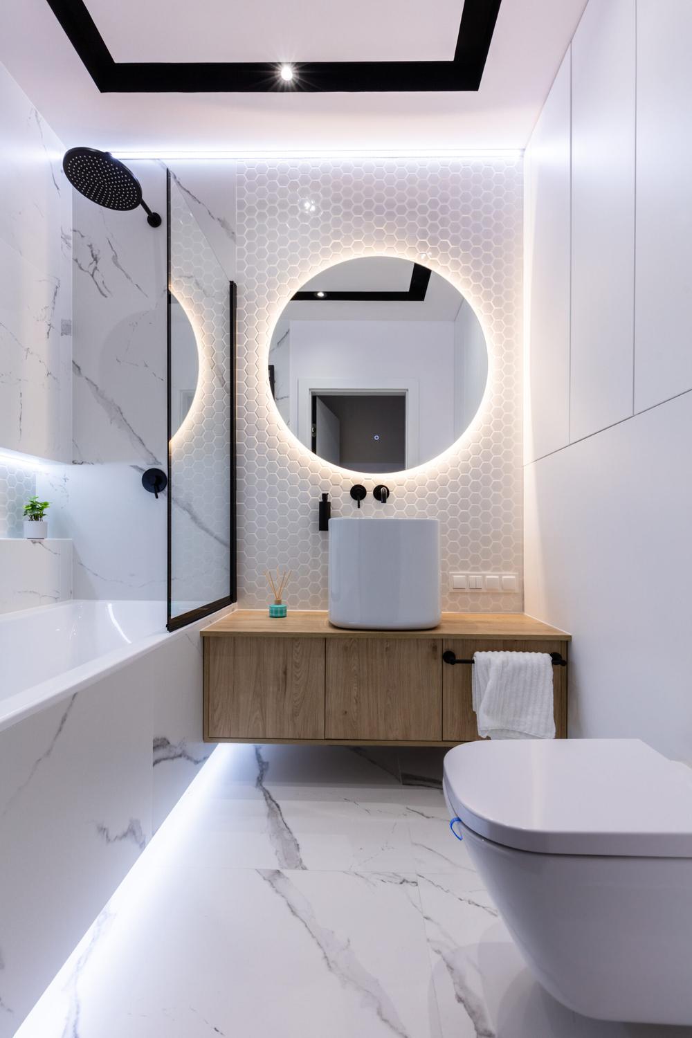 Sleek small bathroom with a minimalist bathtub, circular mirror, and modern fixtures for an airy feel.