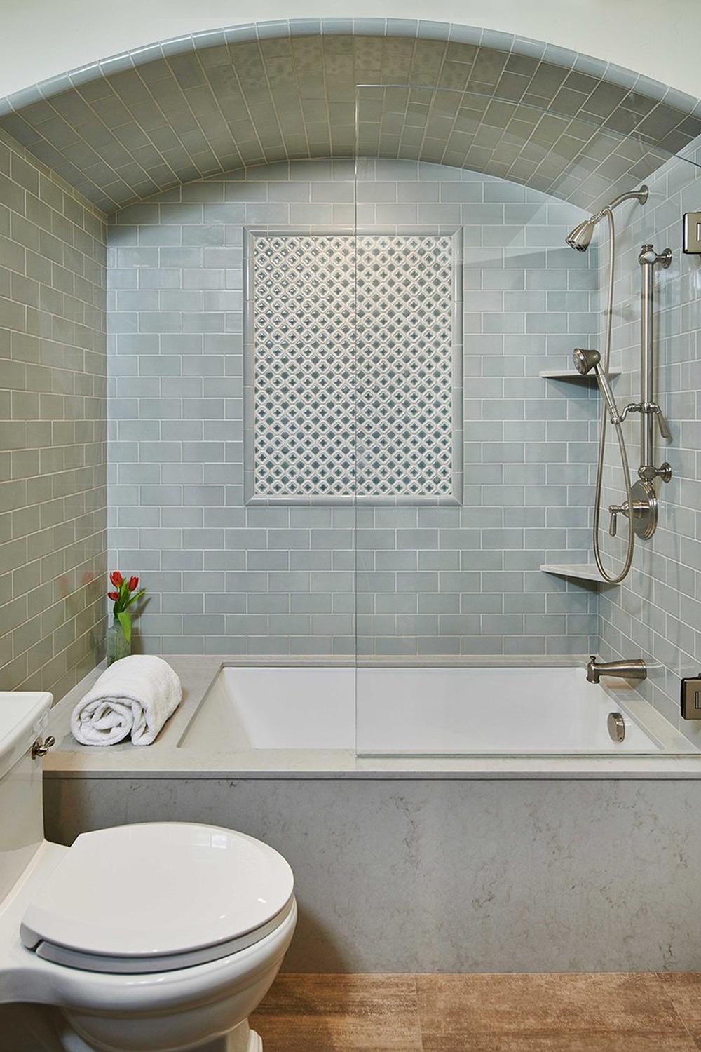 Compact bathroom with a bathtub and shower combo, highlighted by light green subway tiles and well-organized bathroom accessories.