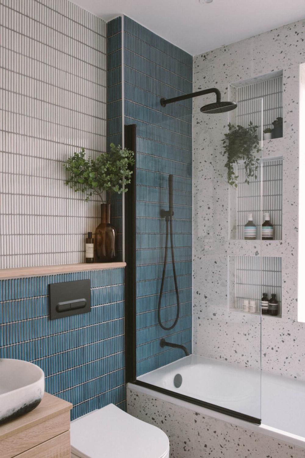 Compact bathroom featuring a jewel-tone bathtub, shower combination, and natural elements for a calming feel.