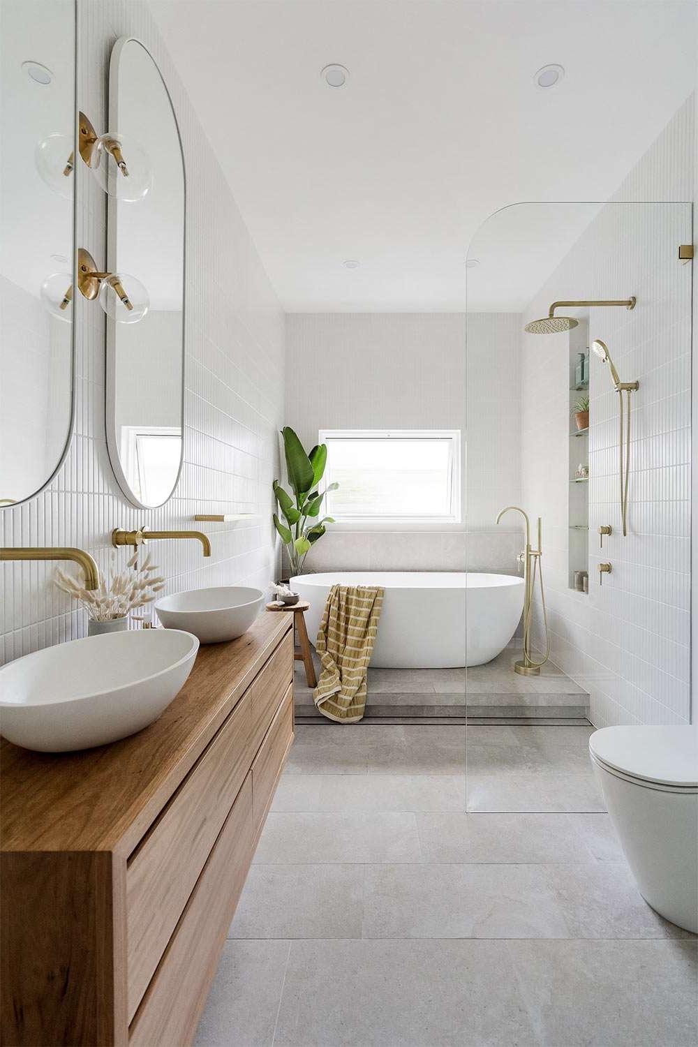 Elegant small bathroom with a sleek bathtub, multiple mirrors, and trendy gold accents for a luxurious look.