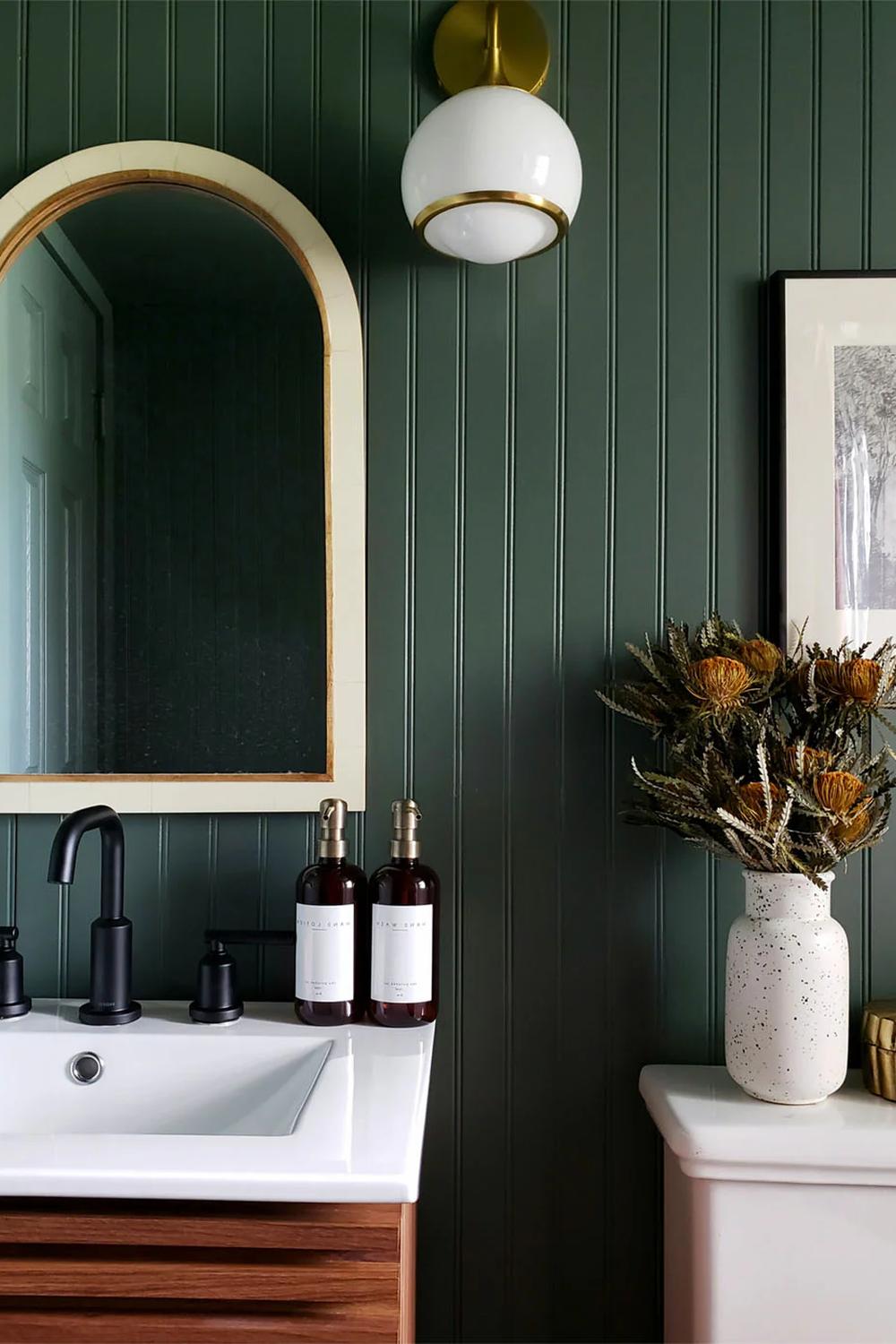 Baño pequeño con paneles y espejo arqueado