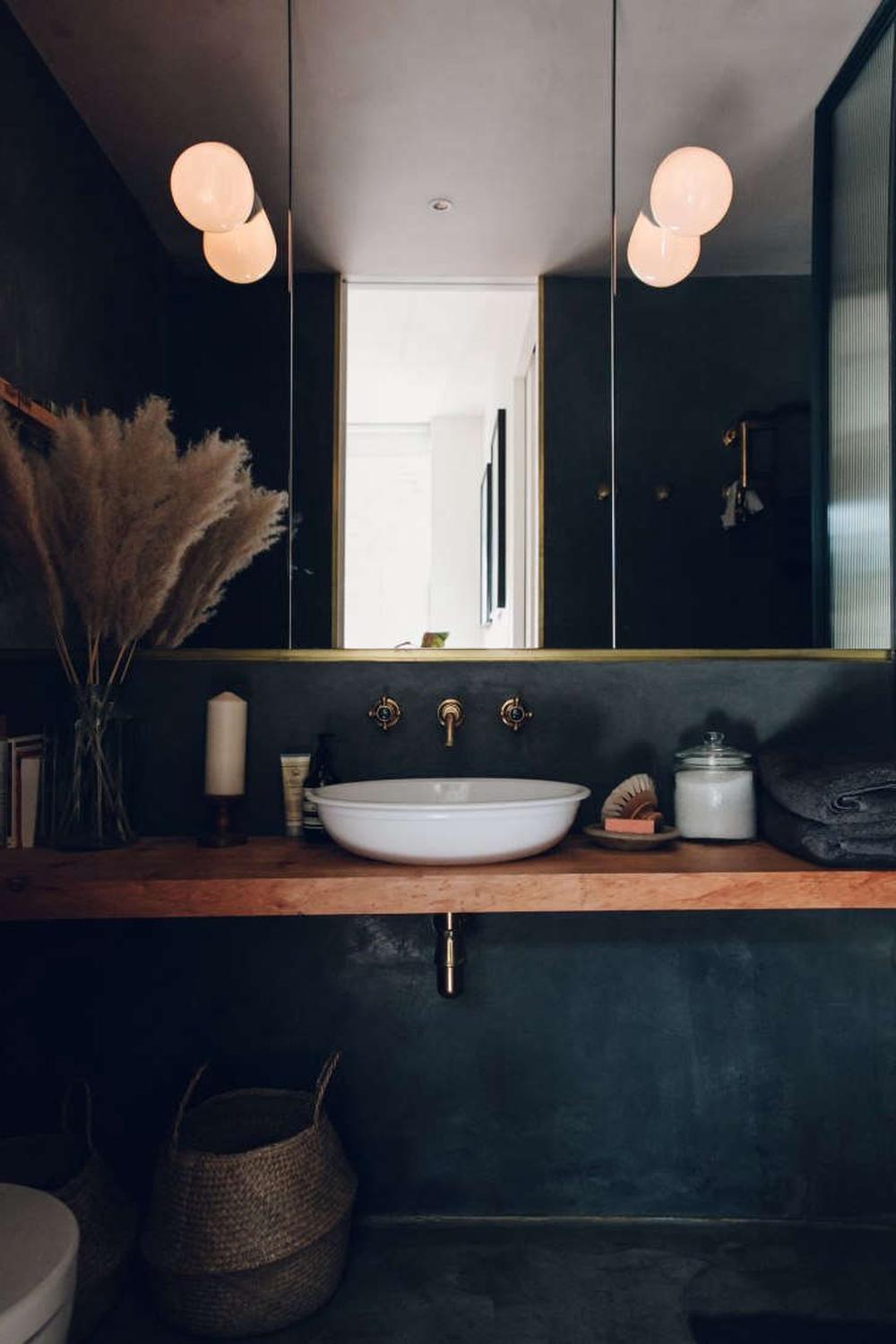 Baño pequeño con abundancia de espejos y tonos profundos