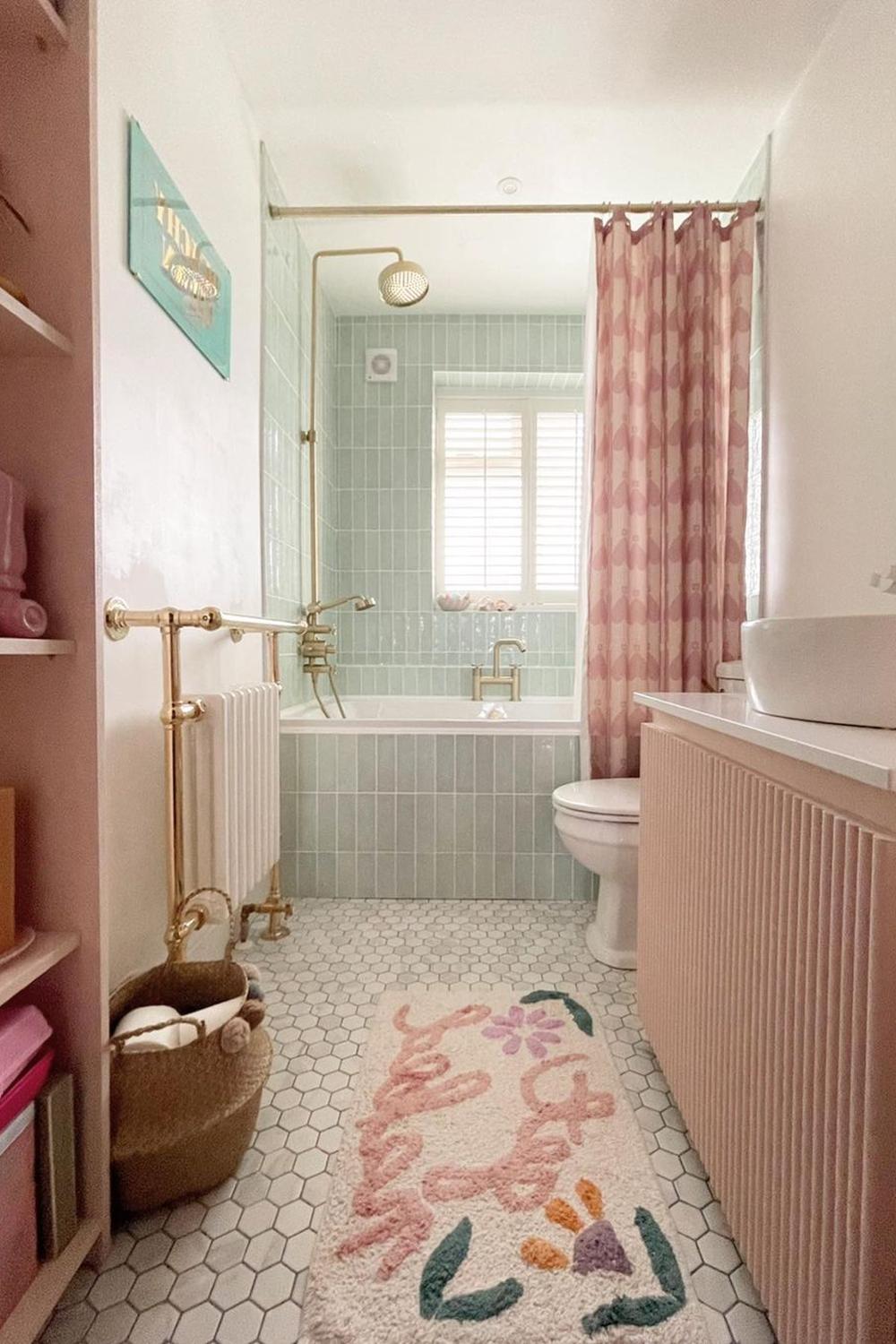 A serene bathroom featuring soft green tiles, a freestanding bathtub, and elegant brass fixtures.