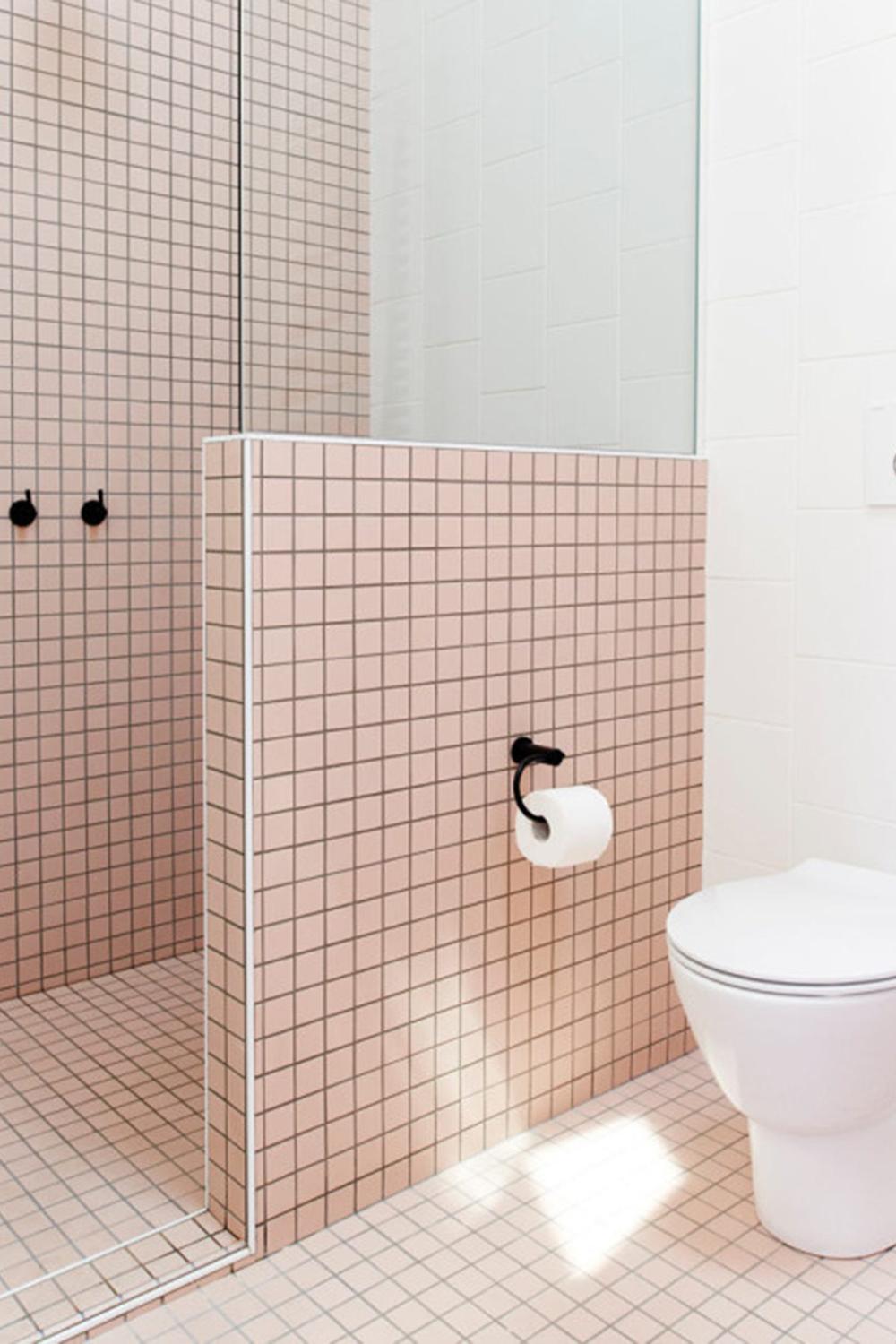 Baño minimalista con azulejos rosa y ducha de cristal