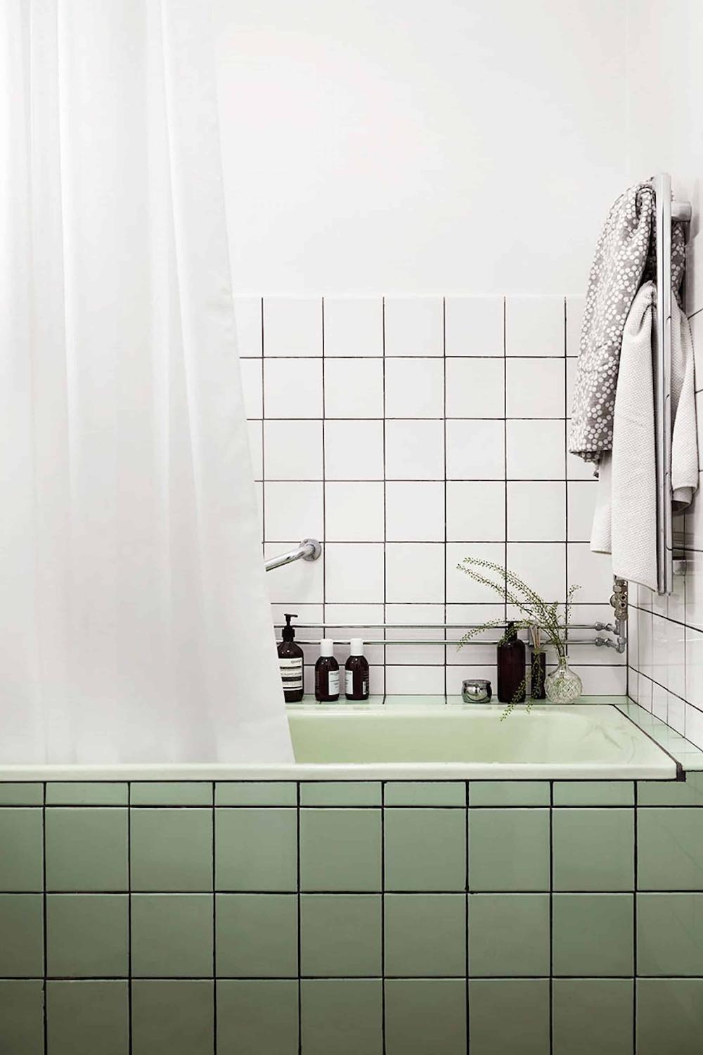 Baño moderno con azulejos verdes y ducha bien equipada