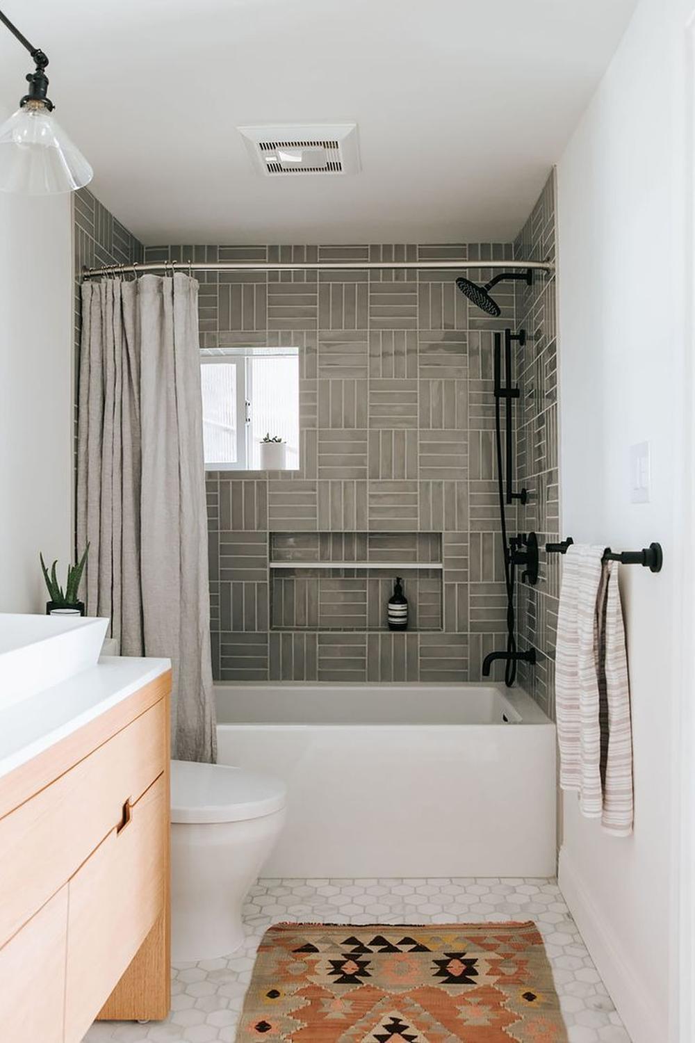 A modern bathroom featuring gray stacked subway tiles and a white bathtub for a serene look.