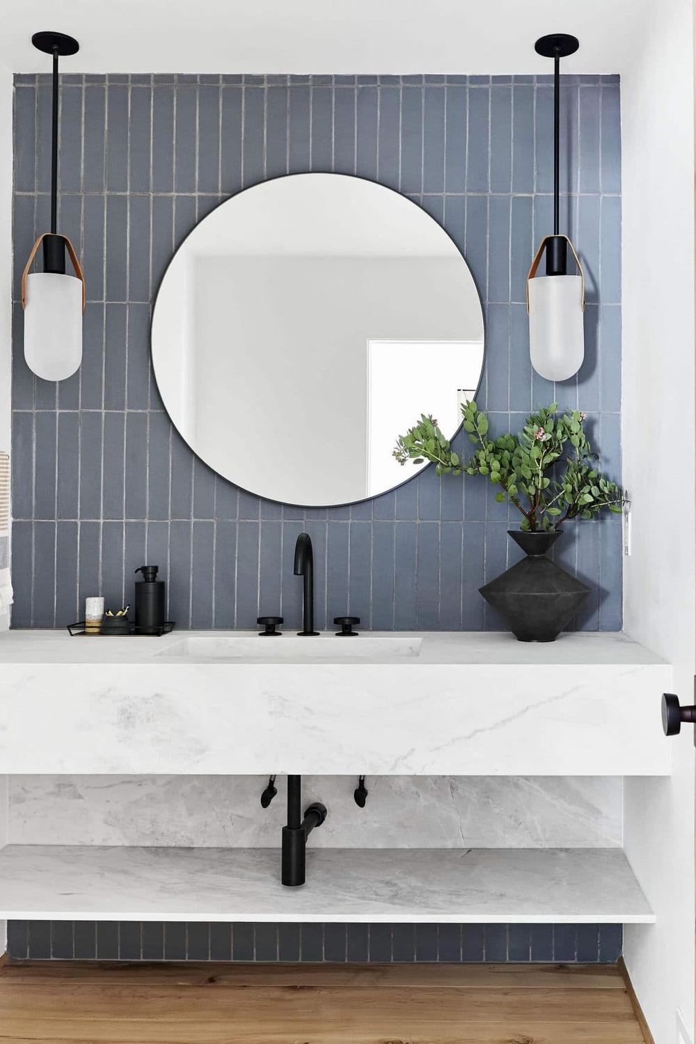 A modern bathroom showcasing muted blue-gray subway tiles and stylish pendant lights.