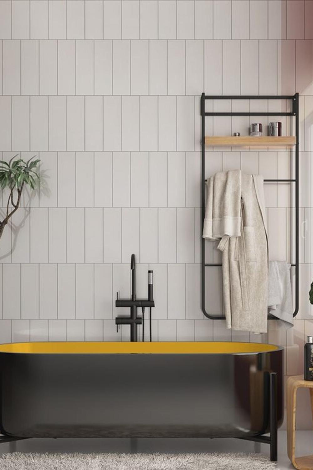 A bold bathroom featuring a dark freestanding bathtub with a yellow interior and subway tiles.