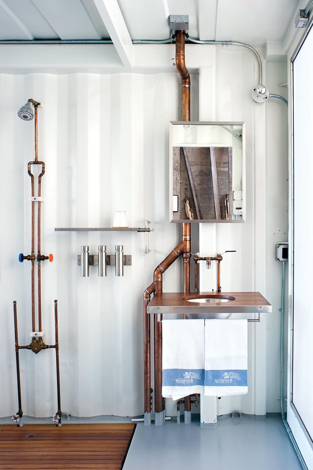 Bathroom featuring a wooden countertop and copper piping, merging rustic and industrial styles.