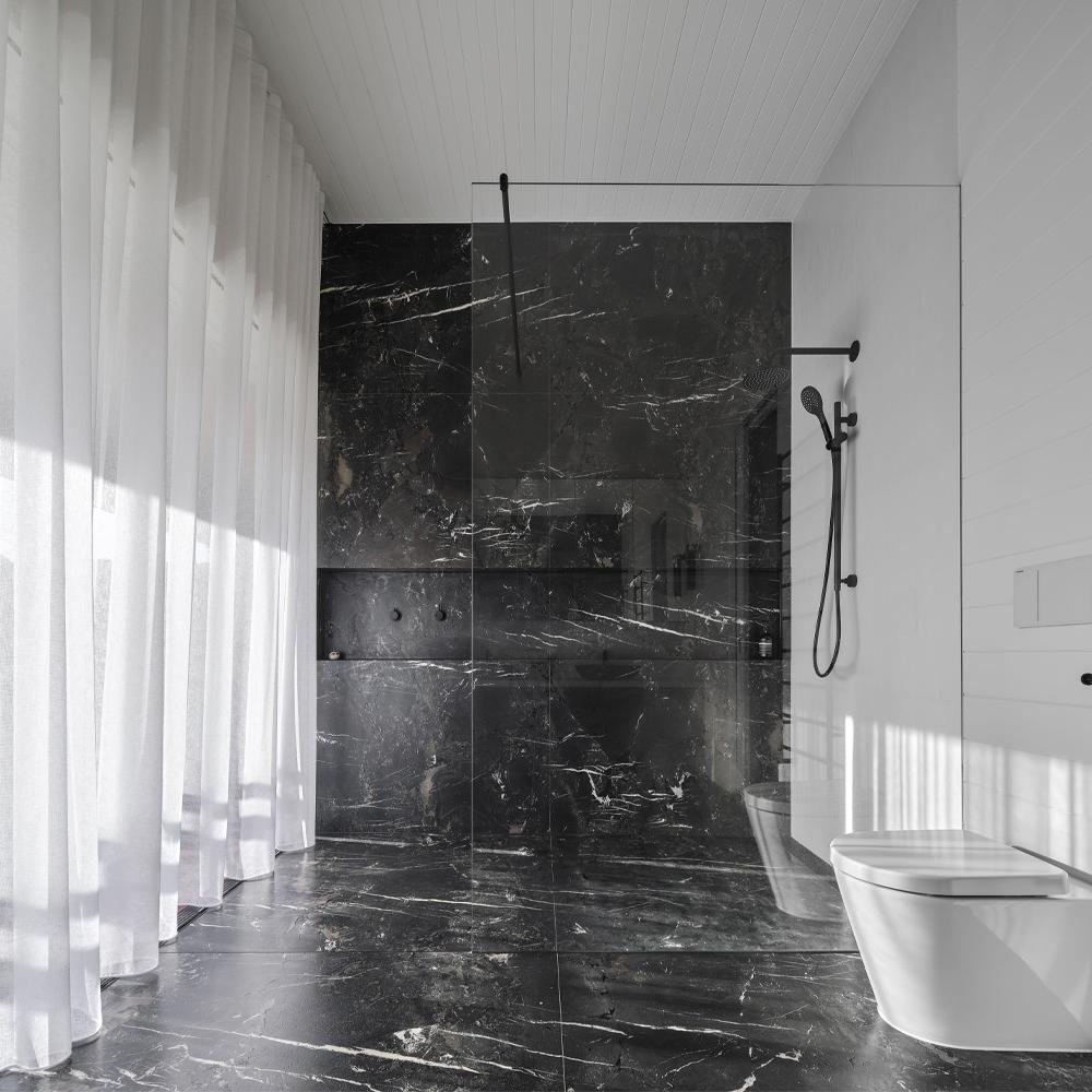 Sophisticated stone bathroom featuring dark polished stone with rich color palette and minimalist details.