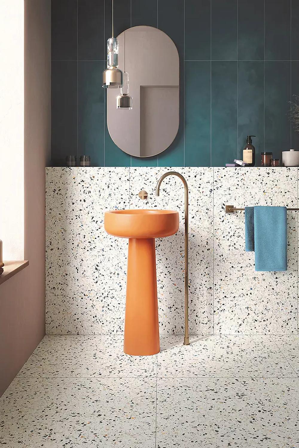 Baño moderno con suelo de terrazo y lavabo pedestal naranja