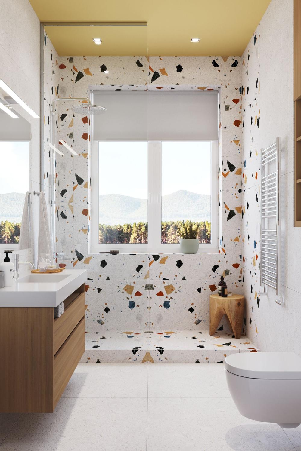 Modern bathroom featuring colorful terrazzo walls with a glass shower partition and wooden vanity.