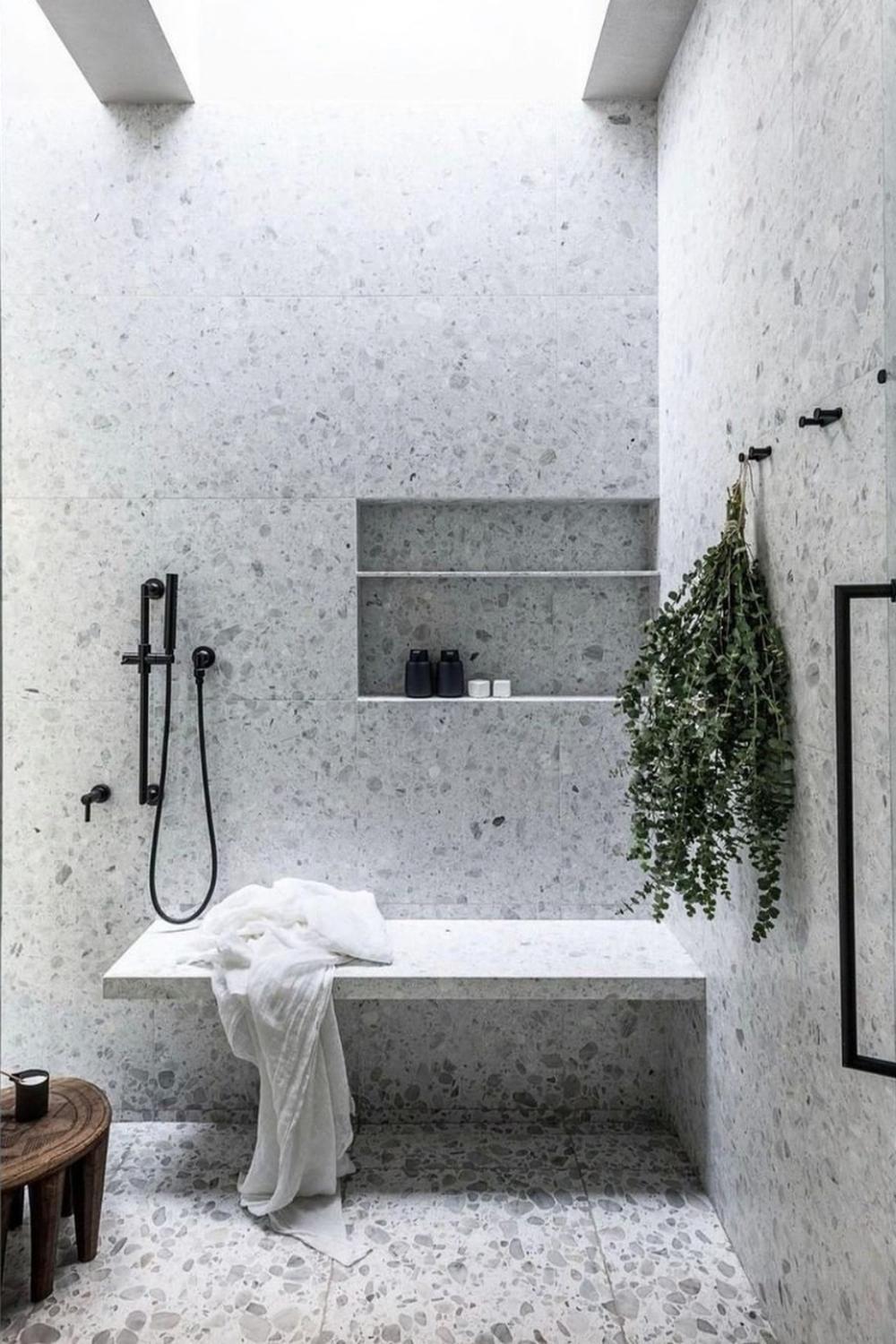 Minimalist bathroom with light-colored terrazzo walls and a spacious shower.