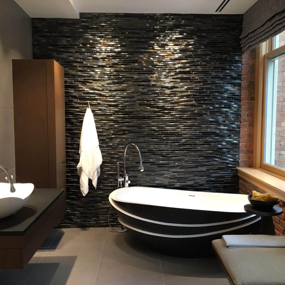 Baño moderno con azulejos negros brillantes y bañera independiente