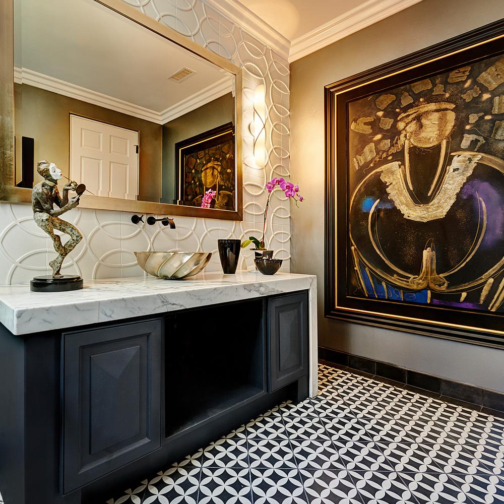 Modern bathroom with a dark cabinetry vanity, abstract wall art, and geometric flooring.