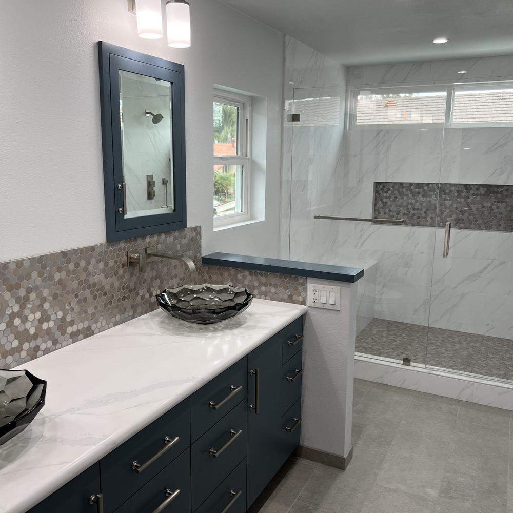 Bathroom with deep teal vanity, marble accents, and natural lighting.