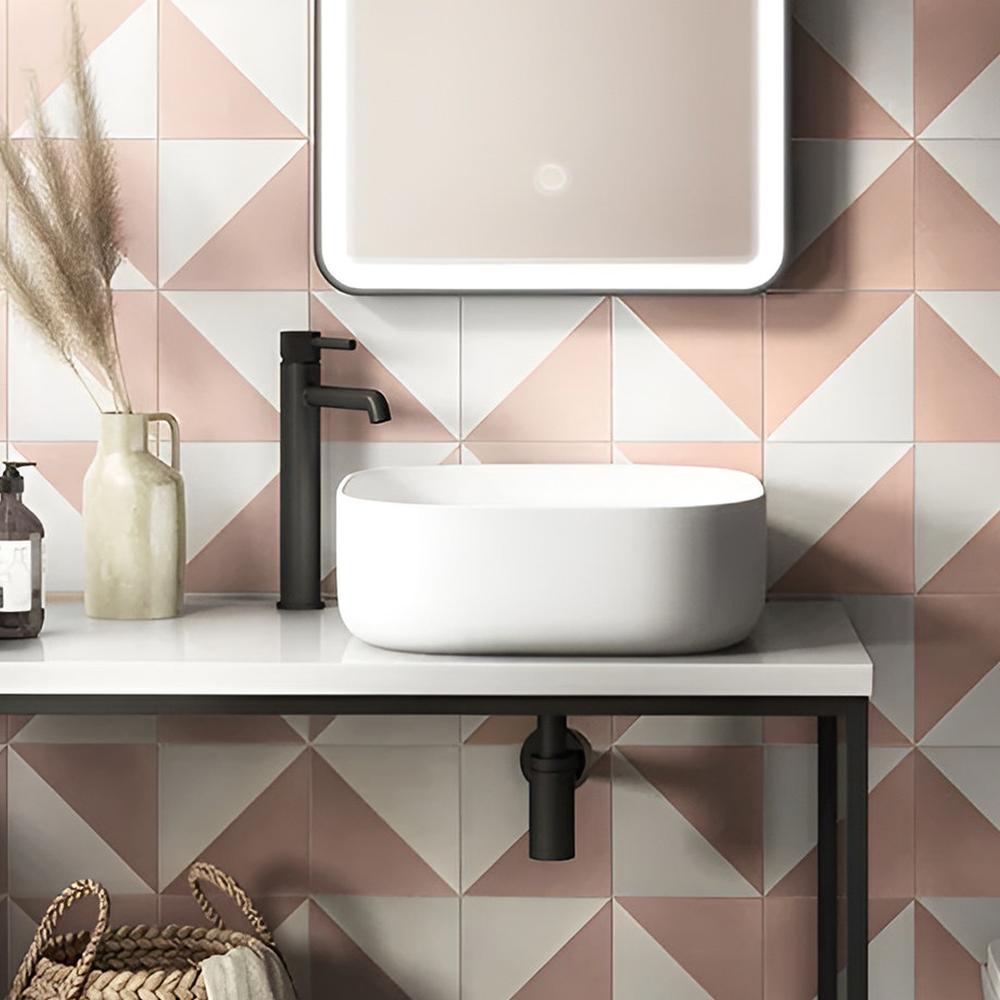Modern tiled bathroom vanity with pink and white geometric tiles and elegant fixtures.