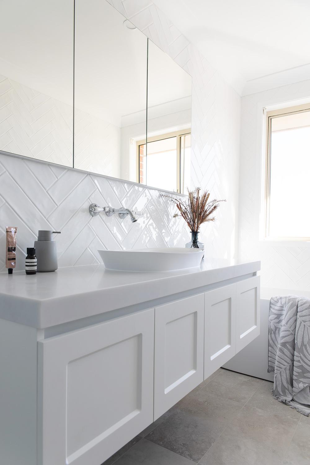 Minimalist bathroom design featuring herringbone tile, a vessel sink, and abundant natural light for an airy ambiance.