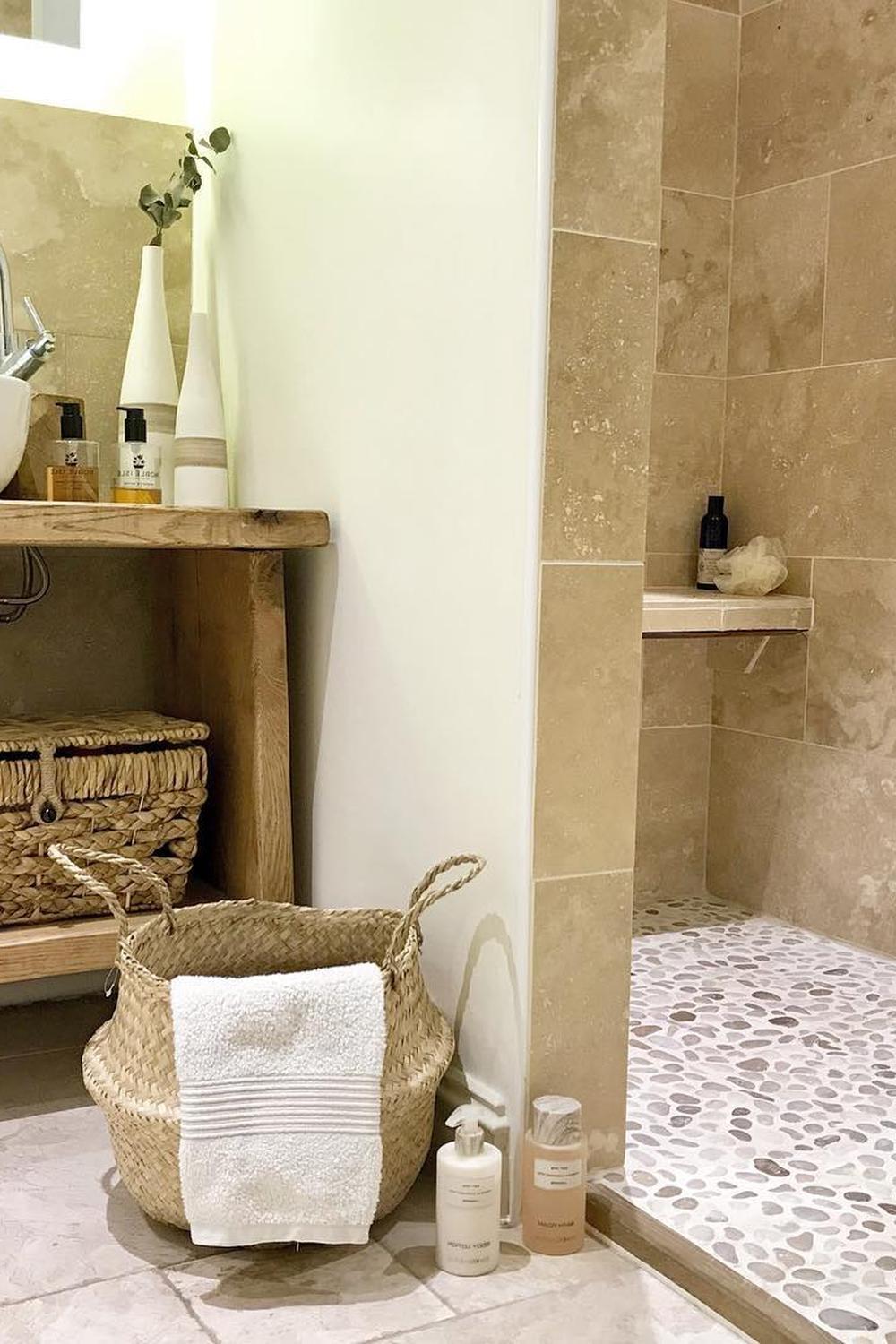 Baño moderno con elementos de travertino y atmósfera relajante.