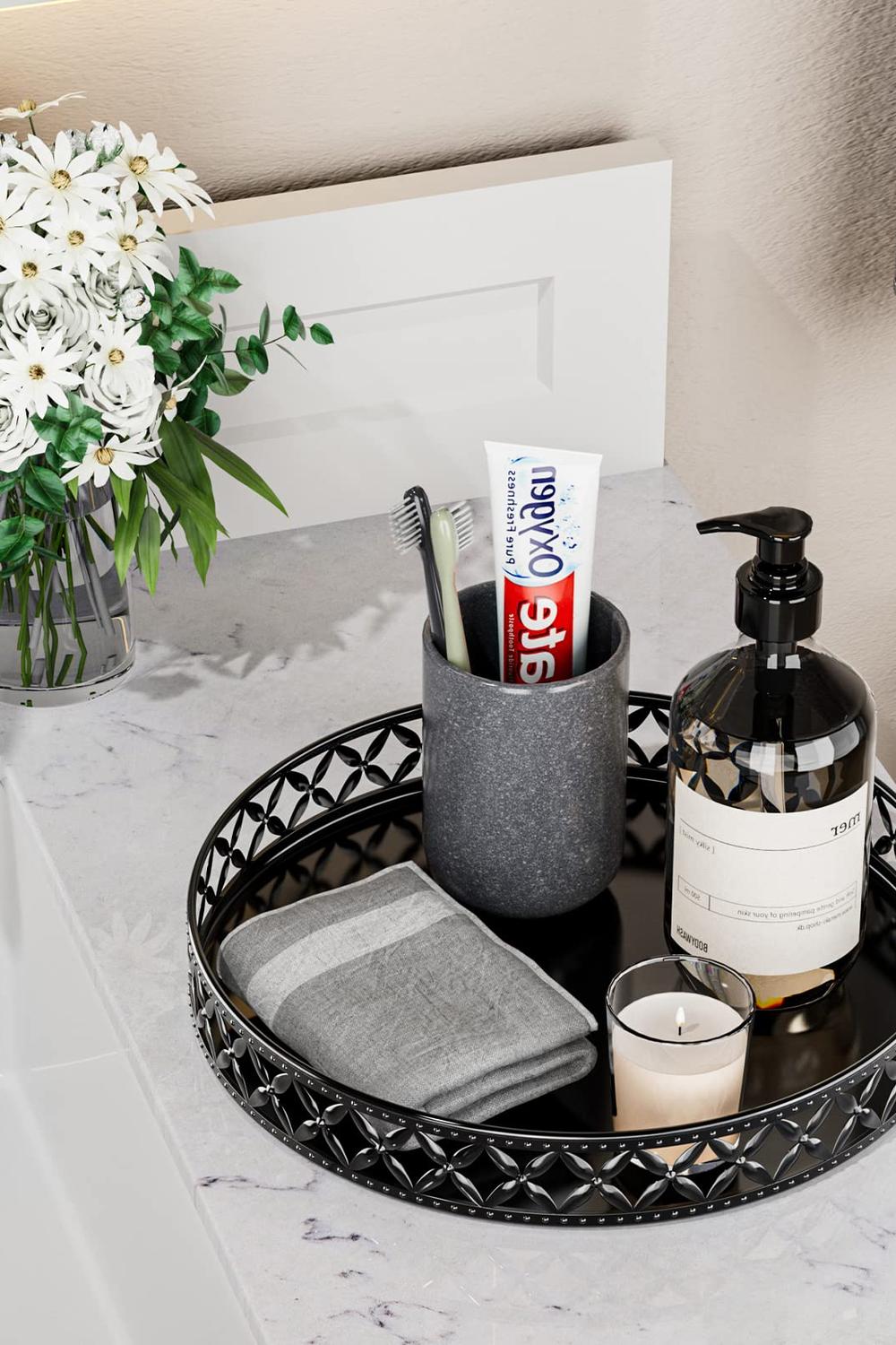 Elegant round black vanity tray with decorative cut-outs, showcasing toothbrush holder, liquid soap dispenser, and candle.