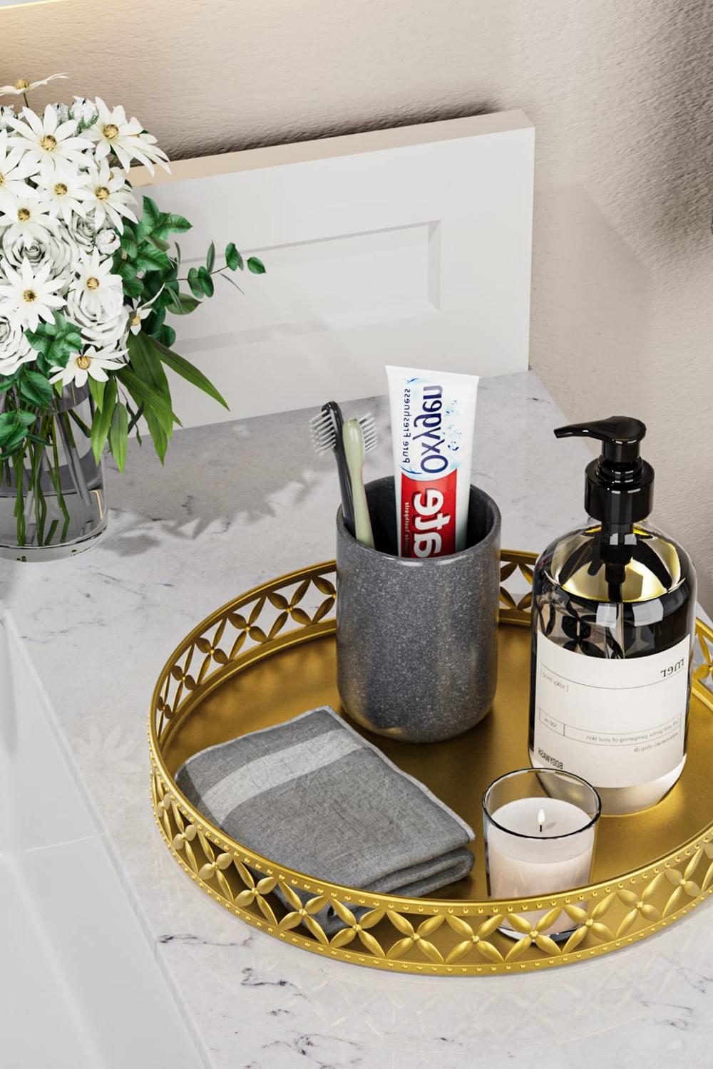 Gold round vanity tray with intricate cut-out pattern, featuring toiletries and a floral arrangement.