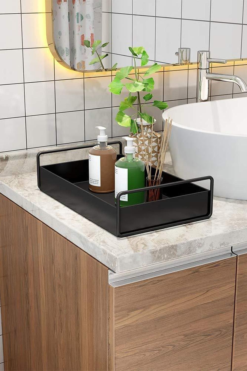 Modern black vanity tray showcasing decorative bottles and a small plant.