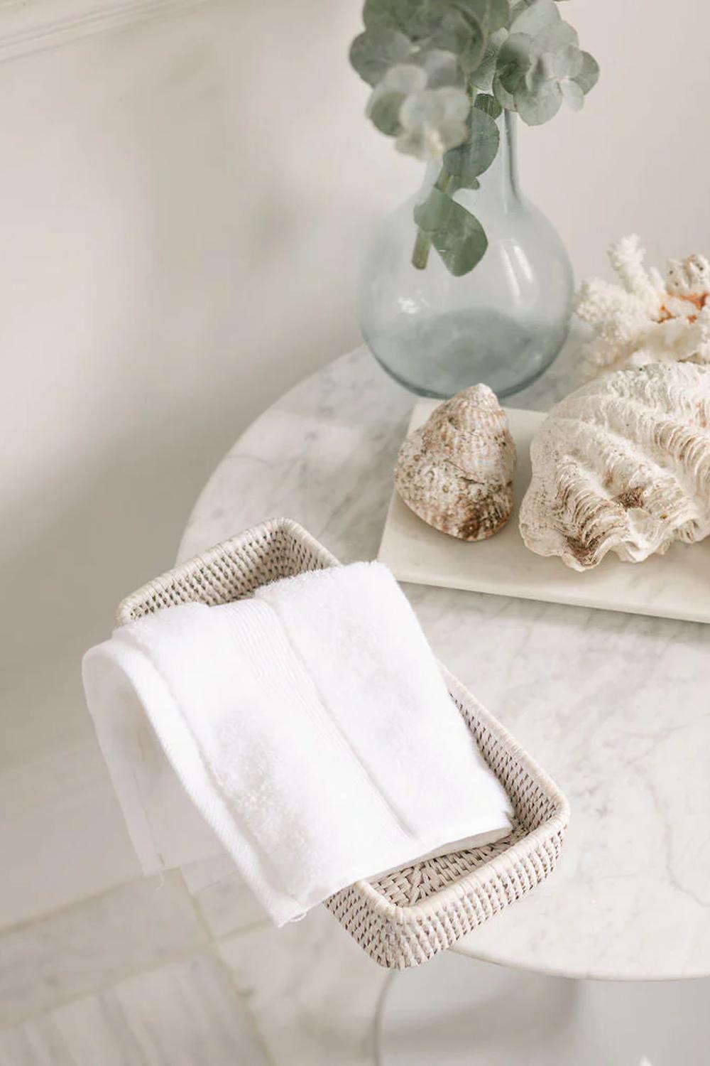 Serene woven vanity tray with plush white towels and eucalyptus accents.