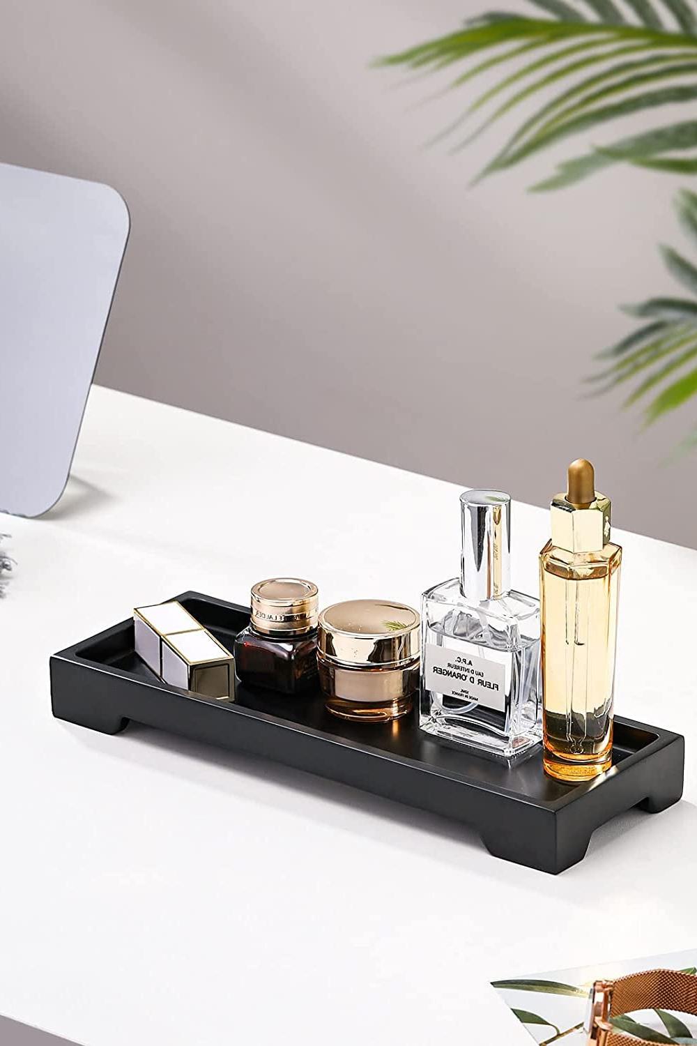 Minimalist black vanity tray showcasing vibrant cosmetic products and a stylish plant.