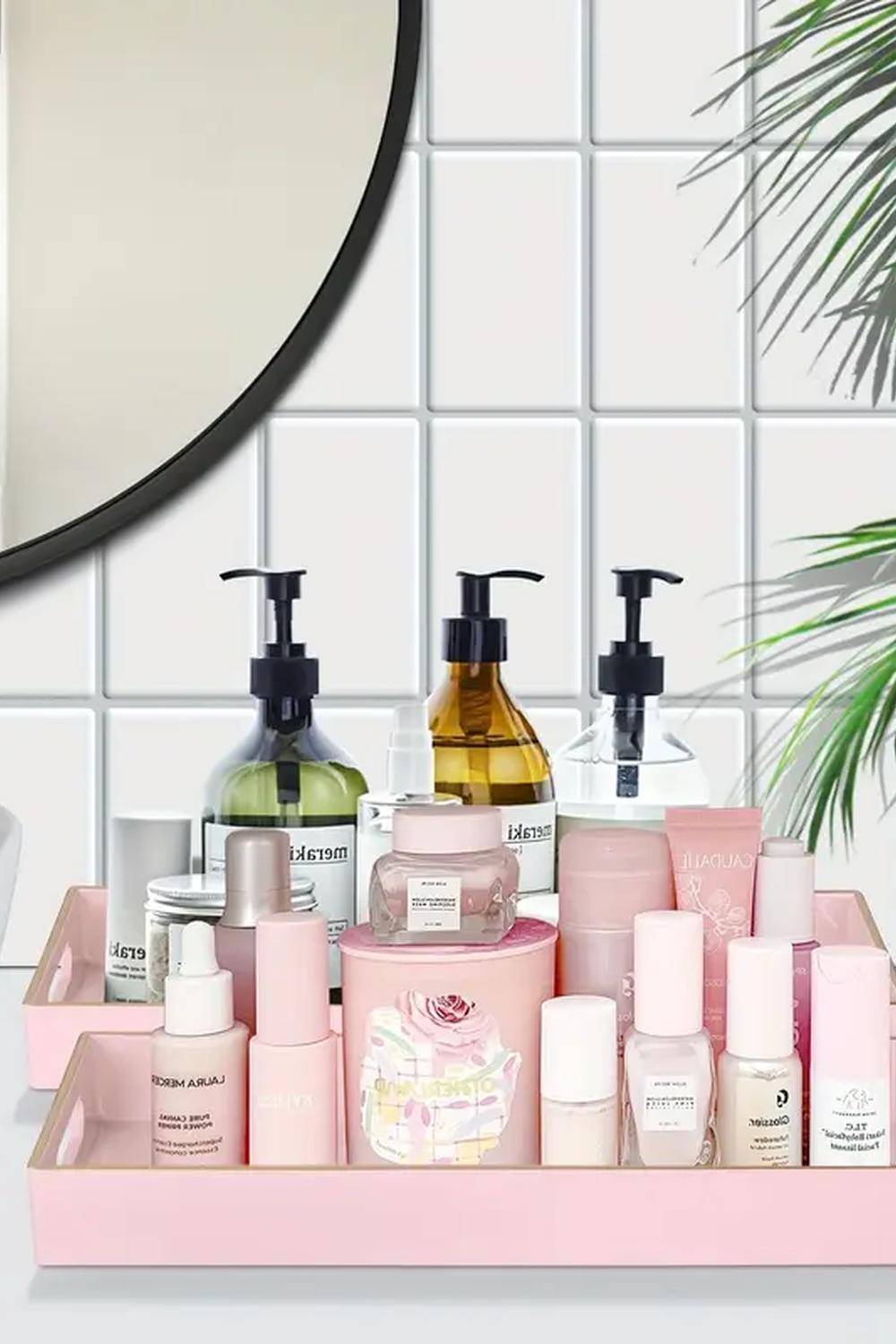 Chic pink vanity tray surrounded by flourishing plants and beauty products.