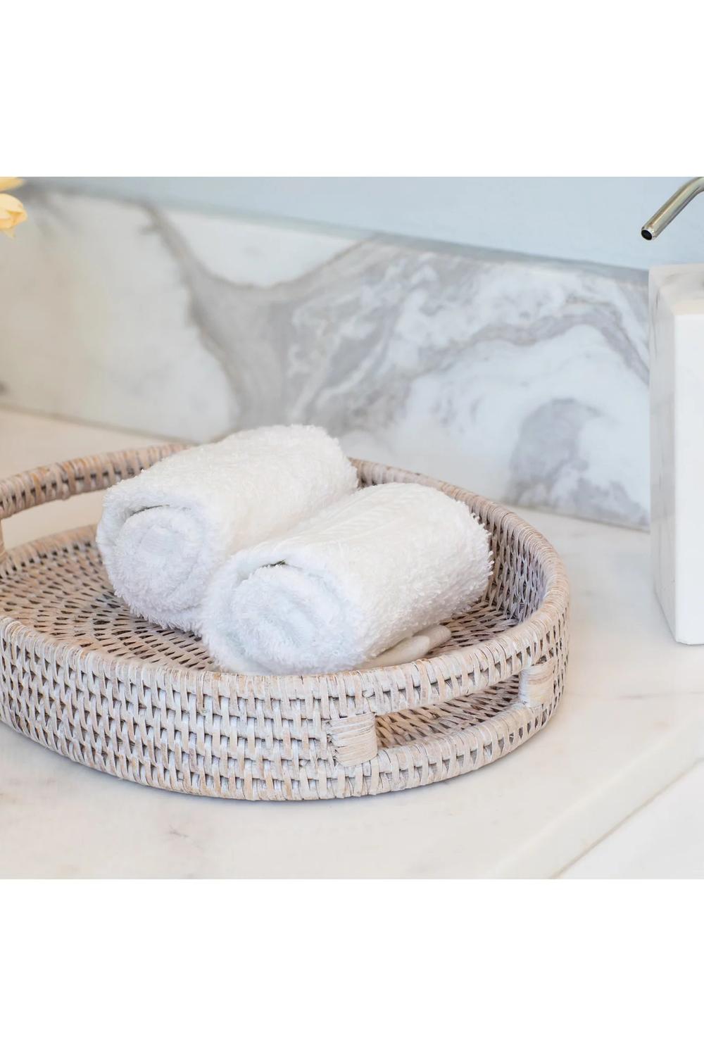 Light-colored woven vanity tray holding luxurious towels.