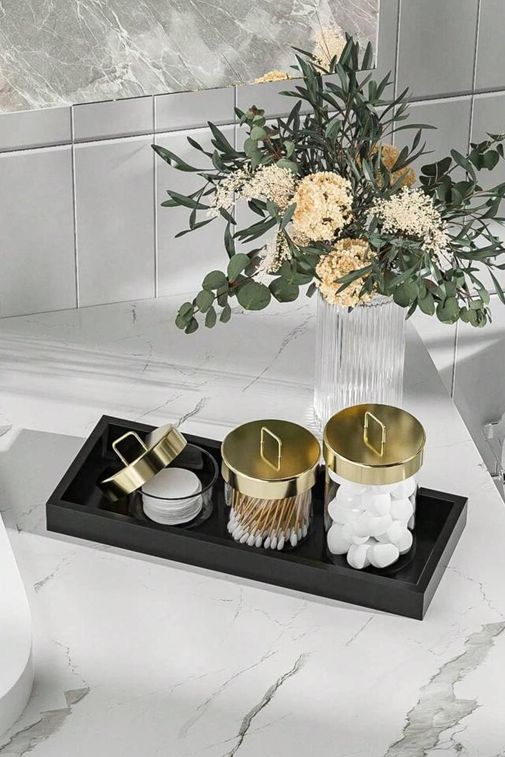 Sophisticated vanity tray with storage jars and a floral arrangement.