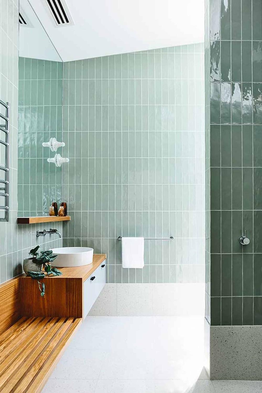 Bathroom featuring soothing mint green vertical subway tiles and a stylish shower area.
