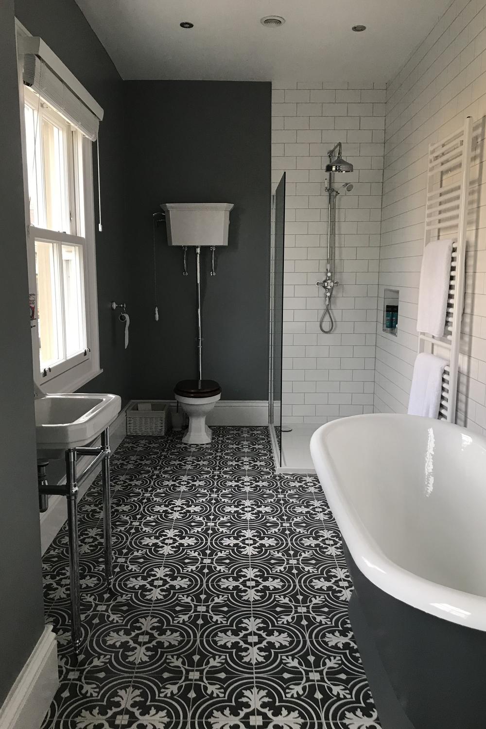 A stylish Victorian-inspired bathroom featuring a dark, muted gray color palette and floral design elements.