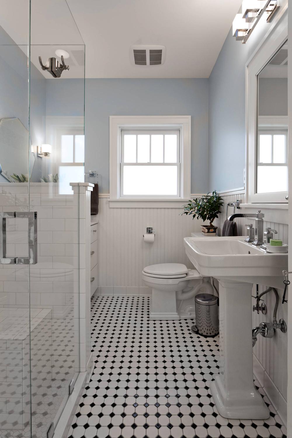 A Victorian-inspired bathroom showcasing soft blue walls and a glass-enclosed shower.