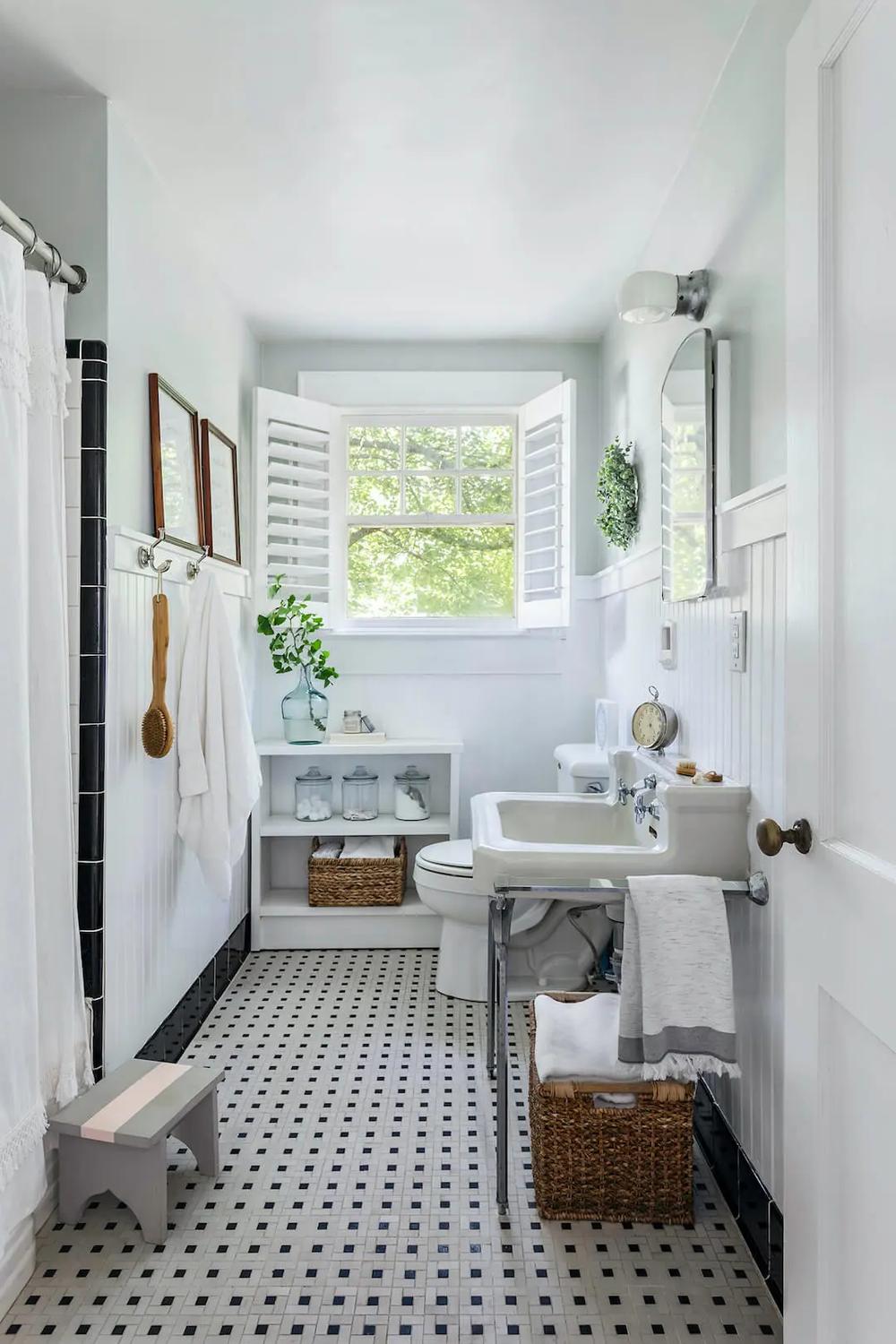 Classic black and white tiled vintage bathroom featuring open shelving and a large window highlighting natural light.