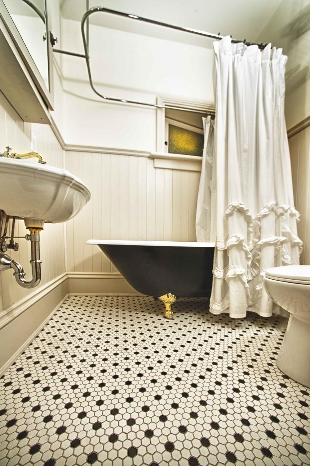 Elegant vintage bathroom with black and white hexagonal tiles and a luxurious freestanding bathtub.