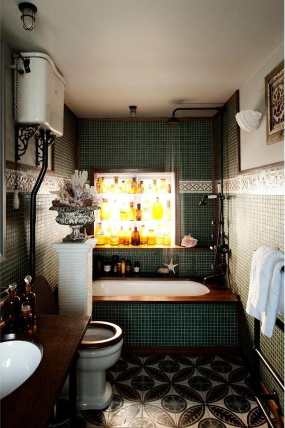 Vintage bathroom with intricate green tiles and decorative storage behind the bathtub.