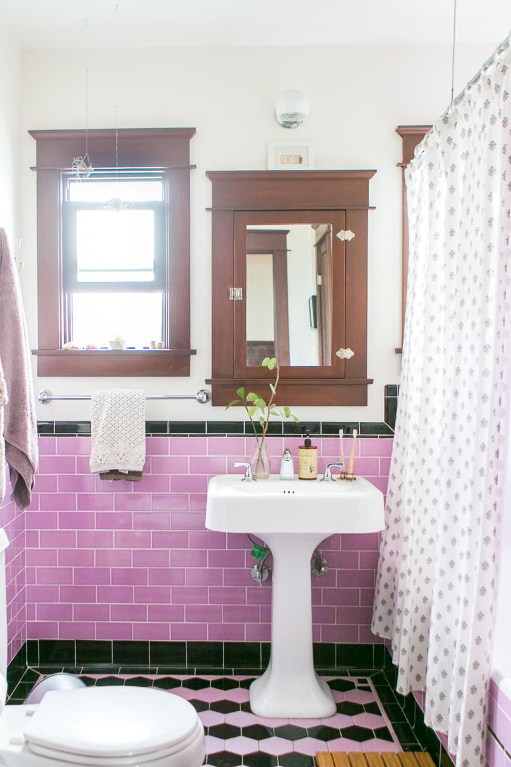 Charming vintage bathroom with pink subway tiles and black accents around a stylish pedestal sink.