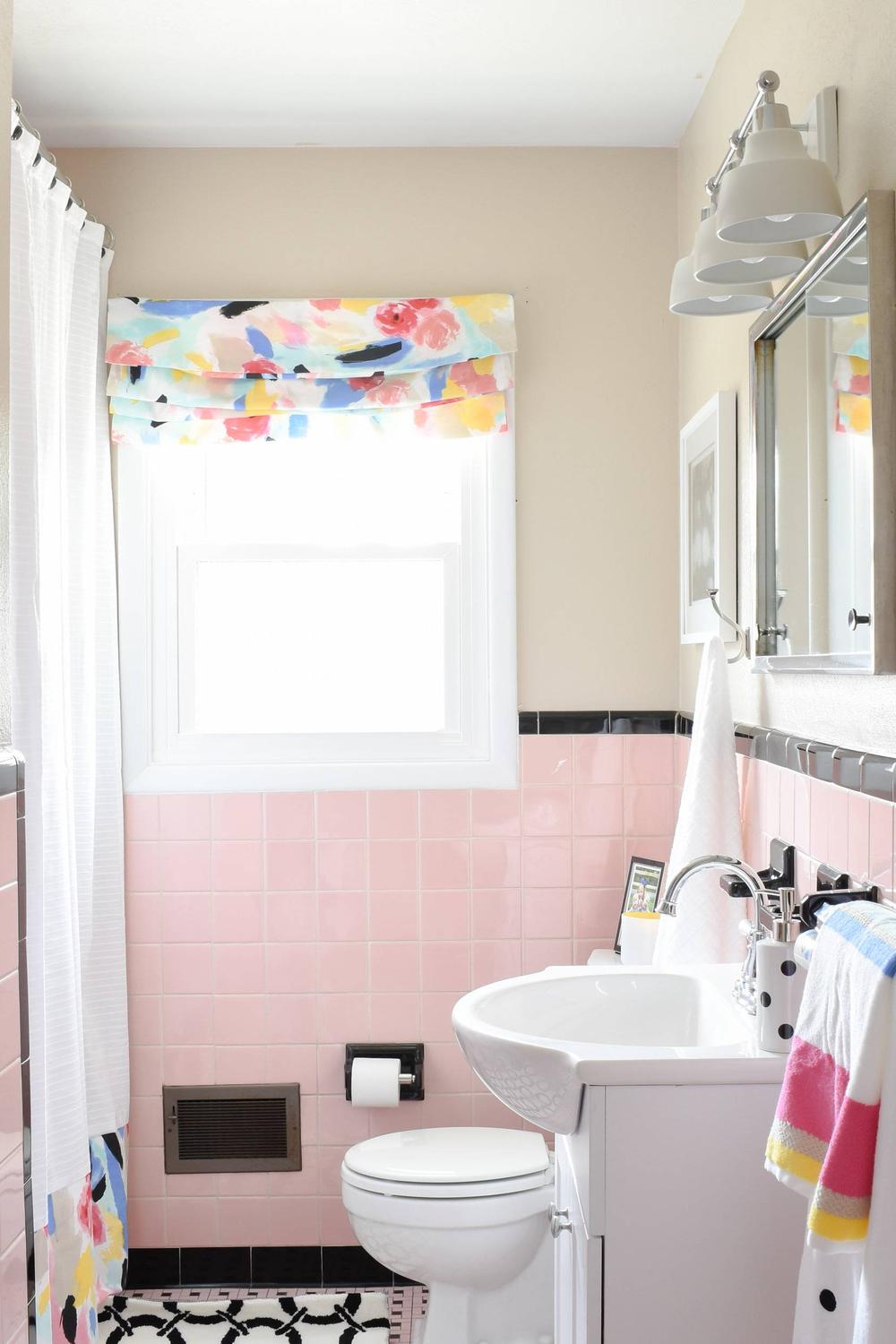 A charming vintage pink tile bathroom with glossy tiles and modern vanity decor.